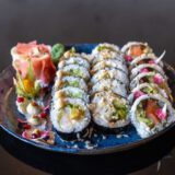 Sushi i dodatki ułożone na niebieskim talerzu